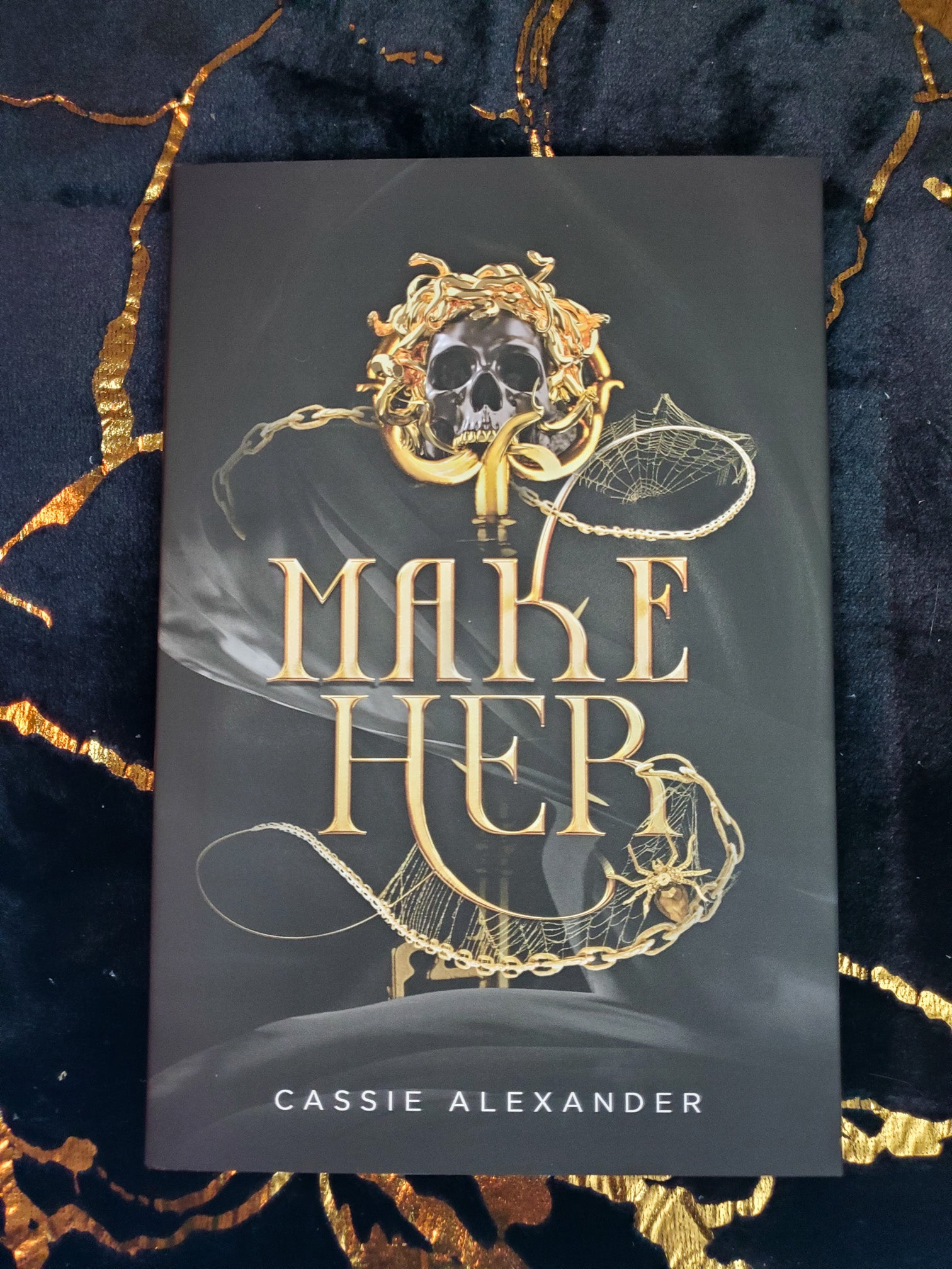 Hardcover of Make Her by Cassie Alexander on a black and gold background. Shows the front cover.