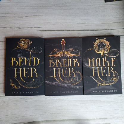 Paperback books of Bend Her, Break Her, and Make Her by Cassie Alexander. 