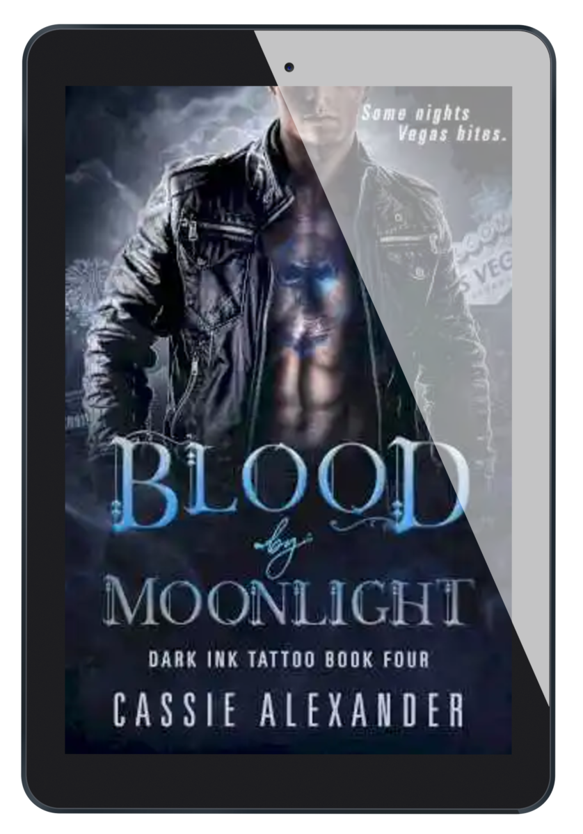 Cover for Blood by Moonlight: Dark Ink Tattoo Book Four by Cassie Alexander. A man wearing a black leather jacket with a blue skull tattoo on his chest stands in front of a Las Vegas skyline. Tagline reads: Some nights Vegas bites. Shown as an ebook on a tablet.