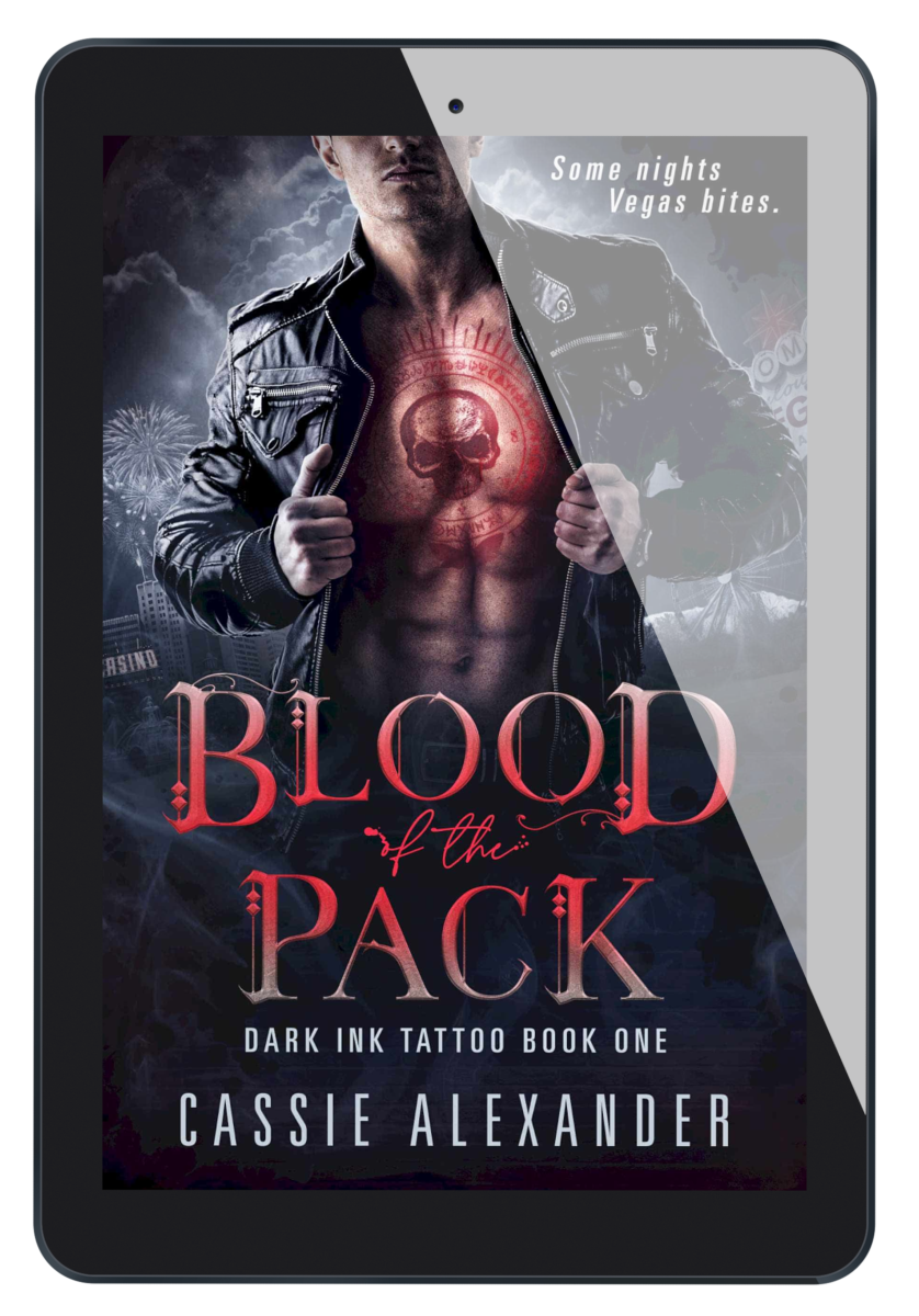 Cover for Blood of the Pack by Cassie Alexander: Dark Ink Tattoo Book One. A buff white man stands holding open a leather jacket. A red skull sits on his chest, rimmed in red sigils. Background is Las Vegas. Tagline reads: Some nights, Vegas bites. Shows an ebook on a tablet.