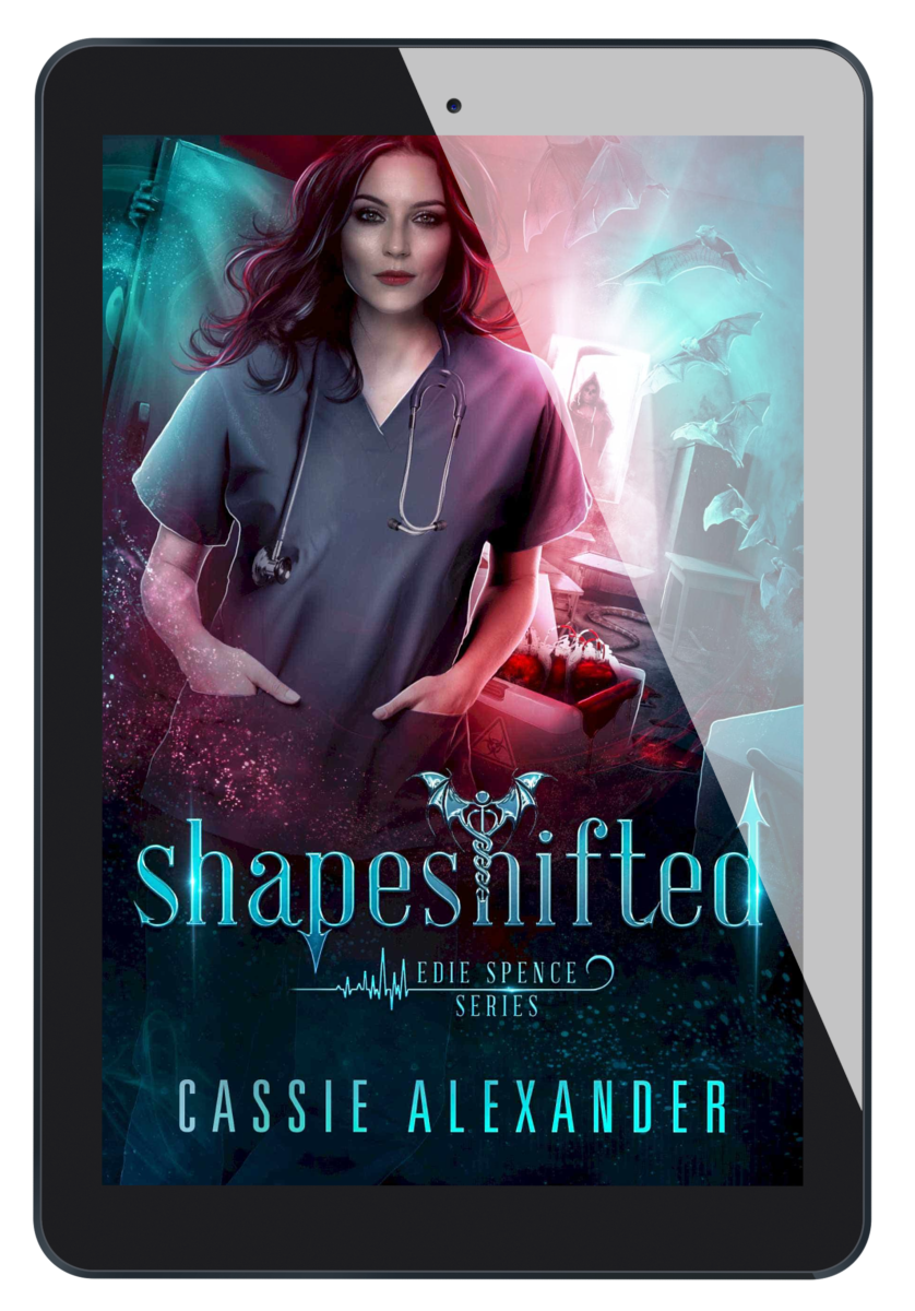 Cover for Shapeshifted: Edie Spence Series Book 3 by Cassie Alexander. A young white woman with shoulder-length brown hair wearing a nurse uniform stands in a hospital corridor, with bats flying around and blood on the floor. Colors are blue and red. Shows an ebook on a tablet.